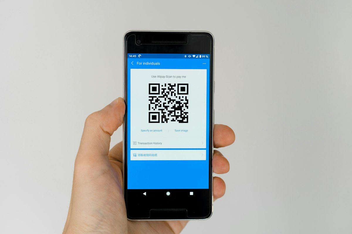 Dłoń trzymająca telefon z kodem QR na ekranie